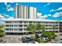 Beautiful exterior shot of condo complex with parking, balconies, and a taller tower in the background against a blue sky at 210 N Ocean Blvd. # 234, North Myrtle Beach, SC 29582
