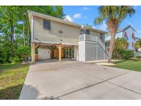 Inviting raised beach home featuring a large driveway, carport, and charming exterior details at 265 South Causeway Rd., Pawleys Island, SC 29585