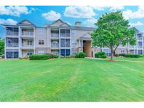Three-story condo building featuring screened porches and a lush green lawn and mature landscaping at 290 Woodlands Way Nw # 10, Calabash, SC 28467