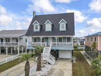 Charming raised beach house with metal roof, white railings, a garage, and tropical landscaping at 312 47Th Ave. N, North Myrtle Beach, SC 29582
