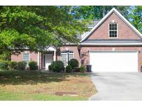 Charming brick home featuring a manicured lawn, mature trees, and an attached two-car garage at 4266 Arabella Way, Little River, SC 29566