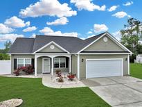 Charming single-story home with a manicured lawn, attached garage, and inviting front porch framed by red rose bushes at 561 Irees Way, Longs, SC 29568