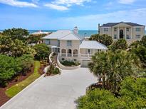 Stunning coastal home with a white facade, metal roof, lush landscaping and scenic ocean views at 109 Pioneer Loop, Georgetown, SC 29440