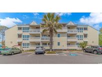 Attractive multi-story condo building with large balconies and lush palm tree in front at 1100 Possum Trot Rd. # H136, North Myrtle Beach, SC 29582