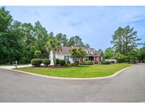 Charming curb appeal with lush lawn, mature trees, and a mix of brick and siding on this two story home at 12 Gloucester Pl., Pawleys Island, SC 29585