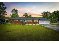 Charming brick home featuring a well-manicured lawn, a blue front door, and an attached two-car garage at 153 Busbee St., Conway, SC 29526