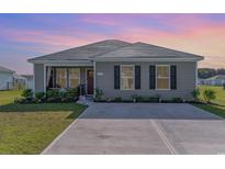 Charming single-story home featuring a well-manicured lawn, neutral siding, and a cozy front porch area at 231 Jeff Waters Circle, Longs, SC 29568