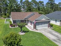 Beautiful single-story home featuring brick accents, vinyl siding, two-car garage, and meticulously manicured landscaping at 255 Tibton Circle, Myrtle Beach, SC 29588