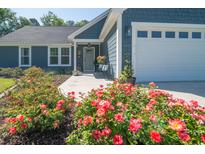 Charming home exterior featuring a two-car garage, blue siding, and a landscaped front yard with roses at 294 Field Loop Rd., Georgetown, SC 29440