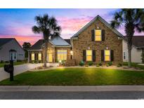 Charming brick home with a well-manicured lawn and palm trees, set against a vibrant sunset sky at 4311 Grovecrest Circle, North Myrtle Beach, SC 29582