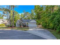 Attractive home exterior with a long driveway, attached garage, and mature trees in a landscaped yard at 5 Old Barge Dr., Pawleys Island, SC 29585
