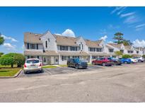 Townhomes with white siding, black shutters, and parking in front on a sunny day at 500 Fairway Village Dr. # 7-C, Myrtle Beach, SC 29588