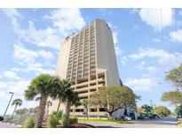 Low angle of high-rise condo building with balconies and parking garage under a partly cloudy sky at 5523 N Ocean Blvd. # 1201, Myrtle Beach, SC 29577