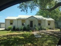 Charming home featuring a metal roof, yellow window awnings, and mature landscaping at 640 Willowbank Rd., Georgetown, SC 29440