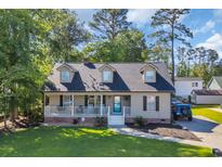 Charming home with a welcoming front porch, lush lawn, and driveway featuring a blue Jeep at 6864 Woodhaven Dr., Myrtle Beach, SC 29588