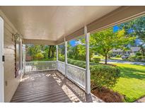 Inviting covered porch with wooden flooring, white railings, and views of the landscaped front yard at 7602 Glenwood Dr., Myrtle Beach, SC 29572