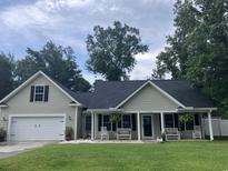 Charming single-Gathering home featuring a 2-car garage, a covered front porch with benches and black shutters at 113 Edwards Ln., Longs, SC 29568
