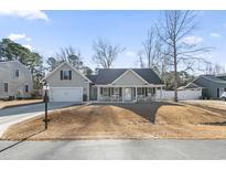 Charming single-story home features a welcoming front porch, attached garage, and manicured lawn at 113 Edwards Ln., Longs, SC 29568