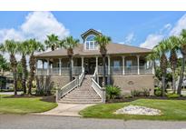 Stately two-story home with a grand staircase, full front porch, and lush landscaping with mature palm trees at 130 Pier Pointe Dr., Little River, SC 29566
