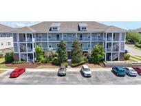 Three-story condo building featuring multiple balconies, a landscaped courtyard, and ample parking at 200 Castle Dr. # 1369, Myrtle Beach, SC 29579