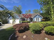 Charming blue home boasts an inviting entrance framed by lush landscaping, stone accents and a manicured lawn at 2333 Brick Dr., Longs, SC 29568