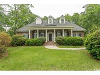 Traditional brick home with a columned front porch and manicured lawn offers Southern charm at 4535 Carriage Run Circle, Murrells Inlet, SC 29576