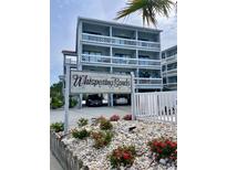 Beautiful three story condo with white railings and Whispering Sands sign at the entrance with landscaping and parking at 625 North Waccamaw Dr. # 101, Murrells Inlet, SC 29576