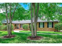 Charming brick home with mature trees, lush landscaping, and inviting walkway on a well-maintained green lawn at 8209 Timber Ridge Rd., Conway, SC 29526
