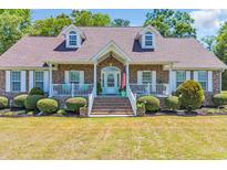 Charming brick home featuring dormer windows, white trim, a welcoming front porch and landscaped yard at 1014 Academy Dr., Conway, SC 29526