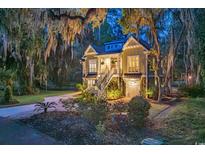 Charming two-story home with a well-manicured lawn and lush landscaping at twilight at 1033 Tuckers Rd., Pawleys Island, SC 29585