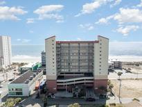 View of a tall condo complex with ocean view and parking, plus surrounding commercial buildings and beach at 1707 Perrin Dr. # 1003, North Myrtle Beach, SC 29582
