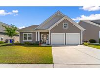 Charming home featuring a two-car garage, well-kept lawn, and appealing architectural details at 194 Zostera Dr., Little River, SC 29566