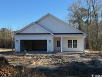 A charming home featuring an attached two-car garage and a welcoming front entrance, set against a natural backdrop at 3597 Valley Forge Rd., Aynor, SC 29511