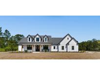 Beautiful white farmhouse exterior with dormers and a manicured front yard at 4426 Still Pond Rd., Conway, SC 29526