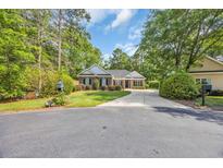 Charming brick home featuring a circular driveway and well-manicured lawn and mature trees at 455 Dornoch Dr., Pawleys Island, SC 29585