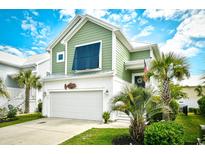 Charming two-story green home featuring a front-facing garage and meticulously landscaped yard with palm trees at 512 Chanted Dr., Murrells Inlet, SC 29576