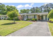 Charming single-story home with a brick and green exterior, carport, and well-maintained landscaping at 558 Juniper Dr., Myrtle Beach, SC 29577