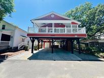 Charming raised red home featuring a white-railed porch and covered parking at 6001 - Z47 S Kings Hwy., Myrtle Beach, SC 29575