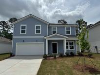 Charming two-story home featuring a light blue facade, attached garage and meticulously landscaped yard at 1011 Laconic Dr., Myrtle Beach, SC 29588