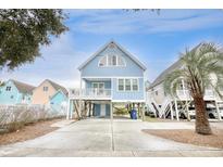 Charming stilted beach house with blue siding, white trim, and a spacious driveway and under house parking at 1023 S Sea Bridge Ct., Surfside Beach, SC 29575