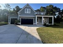 Charming gray two-story home with well-manicured lawn, attached two car garage, and covered front porch at 209 Bouquets Green Way, Myrtle Beach, SC 29579
