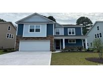 Charming two-story home with stone accents, blue siding, attached garage, and a well-manicured lawn at 7092 Shooting Star Way, Myrtle Beach, SC 29579