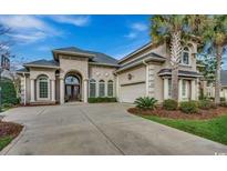 Stunning home featuring a symmetrical elevation, arched windows and entrance, attached garage, palm trees, and a spacious driveway at 9060 Abingdon Dr., Myrtle Beach, SC 29579