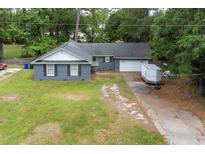 Charming single-story home with a brick facade and a long driveway, surrounded by lush greenery and mature trees at 106 Azalea Dr., Conway, SC 29526