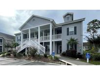 Attractive condo building with covered porches, white railings and stairs, gray siding, and manicured landscaping at 307 Black Oak Ln. # 102, Murrells Inlet, SC 29576