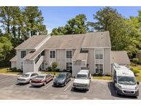 Two-story condo building with multiple parking spaces in front and lush trees surrounding the property at 4470 Little River Inn Ln. # 1005, Little River, SC 29566