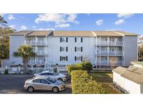 Three-story condo with a light gray exterior, black shutters, and white balconies surrounded by a well maintained landscape at 712 Dogwood Dr. S # 101, Surfside Beach, SC 29575