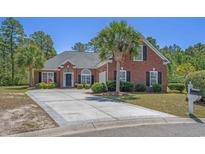 Charming red brick home featuring a well-manicured lawn, palm trees, and a spacious concrete driveway at 832 Pembridge Ct., Myrtle Beach, SC 29579