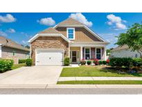 Charming single-Gathering home featuring a stone facade, a well-manicured lawn, and a two-car garage at 962 Witherbee Way, Little River, SC 29566