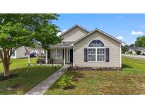 Charming single-story home with a well-manicured lawn, sidewalk, and inviting front porch seating area at 1108 Blue Juniper Ct., Conway, SC 29527